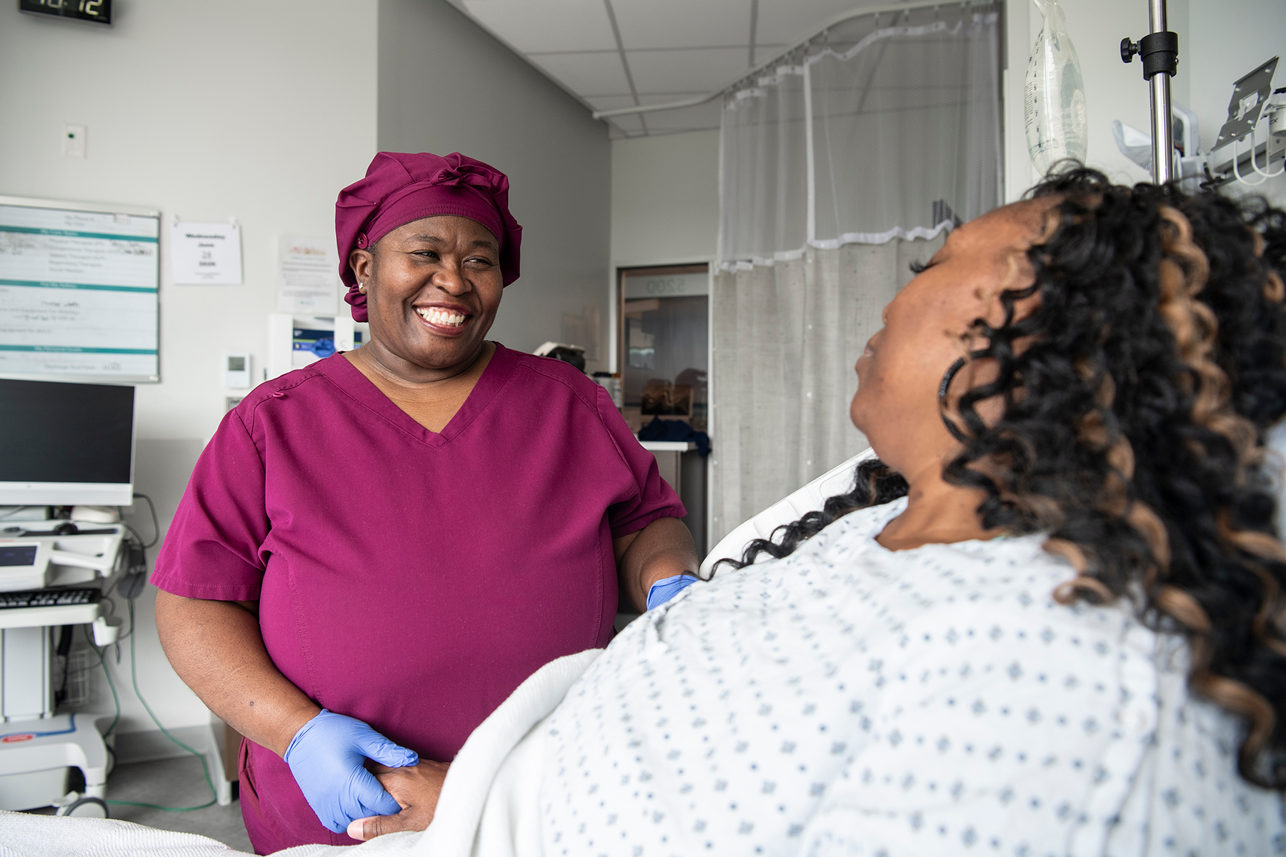 Nurse smiling at patient in hospital bed